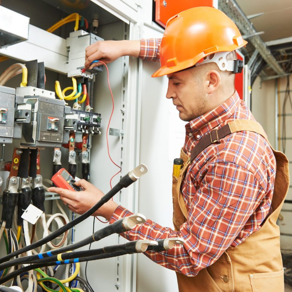 Electrician testing a control panel with a multimeter for Electrical Services.